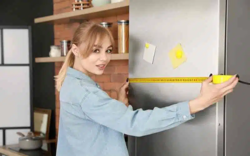 A girl measuring fridge size